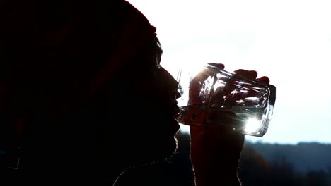high-contrast-clip-of-a-young-caucasian-man-relax-and-drinks-a-glass-of-water--close-up-and-backlight-footage