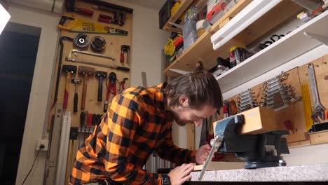 Young-caucasian-hipster-with-checkered-shirt-is-wood-crafting-in-his-garage
