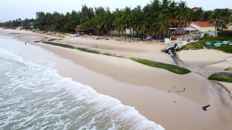 Ocean-waves-destroying-tropical-sandy-beach-by-erosion,-aerial-drone-view