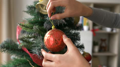 Woman-decorating-Christmas-holiday-tree-at-home-with-red-balls,-close
