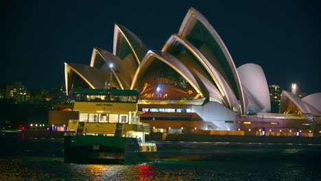 Fährpassagierschiff-Mit-Leeren-Sitzen,-Das-Nachts-In-Sydney,-Australien,-Durch-Den-Hafen-Segelt-Und-Einen-Malerischen-Blick-Auf-Das-Dahinter-Liegende-Opernhaus-Bietet