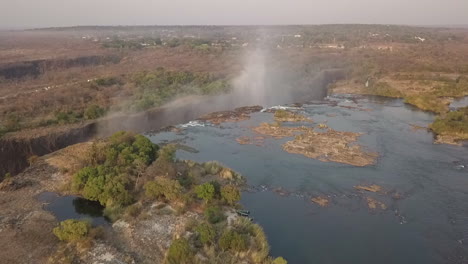 Orbiting-aerial-of-famous-Victoria-Falls-with-subtle-rainbow-in-mist