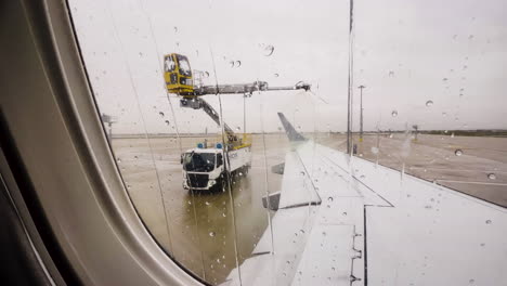 De-Icing-Truck-Sprays-Wing-Of-Plane,-Seen-From-Passenger-Seat-Window