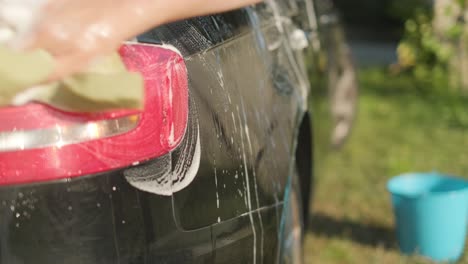 Doing-circles-with-water,-foam,-soap-and-a-sponge-over-the-body-of-sedan-car