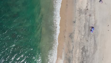 Top-down-aerial-shot-of-sea-waves-crashing-into-the-sand-on-a-beach
