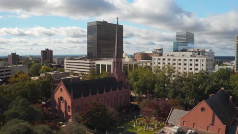 An-aerial-of-First-Presbyterian-Church-in-Columbia,-South-Carolina,-including-the-skyline-from-right-to-left