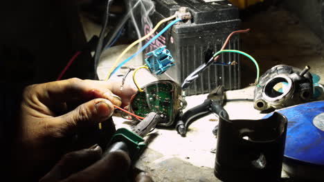 Close-up-view-of-hand-of-a-man-soldering-piece-of-electric-equipment-in-indoor-shop