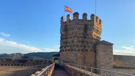 Spanish-flag-waving-on-medieval-Castle-of-the-Mendoza-in-Manzanares-el-Real,-Spain