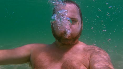 Unterwasseransicht-Eines-Bärtigen-Mannes-In-Apnoe,-Der-Luft-Ausatmet,-Um-Blasen-Zu-Erzeugen