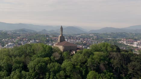 Statue-monument-and-majestic-view-of-San-Sebastian-and-sandy-beaches,-ascending-aerial-view