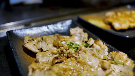 Ein-Japanischer-Koch-Bereitet-Gebratenes,-Geschnittenes-Schweinefleisch-Auf-Einem-Kochherd-Zu,-Um-Die-Gäste-In-Einem-Ambiente-Restaurant-Zu-Speisen