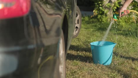 Filling-a-bucket-of-water-with-a-garden-hose-before,-car-washing-process