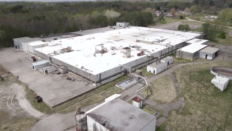 Aerial-Drone-Footage-Orbiting-Around-a-Decaying,-Abandoned-Factory-Surrounded-by-Forests
