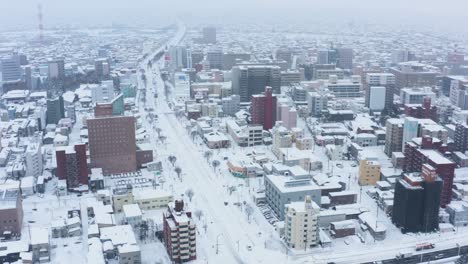 Aomori-City-under-Snow-in-Japanese-Winter,-Aerial-Tilt-Reveal-of-Streets