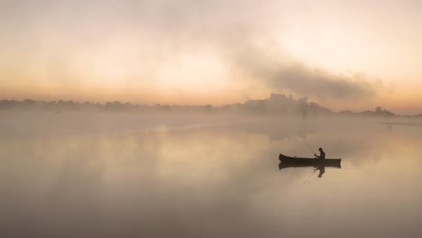 Aerial-apporaching-a-man-fishing-in-a-lake-in-the-early-morning-hours-all-by-himself-at-Imire,-Zimbabwe