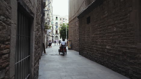 Barcelona---Woman-on-delivery-bike-cycles-through-Gothic-Quarter-streets