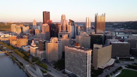 Luftaufnahme-Der-Sonnenbeschienenen-Skyline-Von-Pittsburgh,-Sonnenuntergang-Im-Nordosten-Der-USA---Absteigend,-Drohnenaufnahme