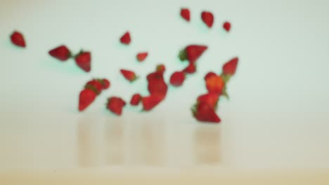 Organic-health-food,-fresh-and-ripe-strawberries-falling-and-rolling-forward-in-slow-motion,-creative-concept-shot