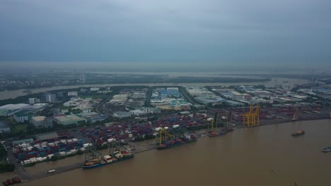 Fly-in-towards-river-and-shipping-port-with-container-ships-being-loaded