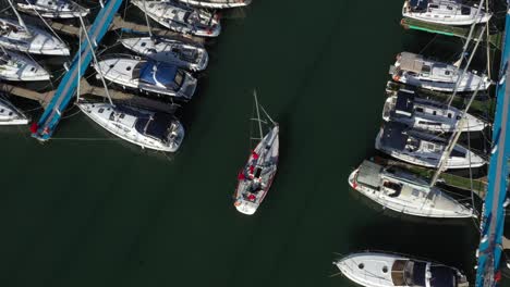Luxury-sailing-yacht-sails-on-her-motor-in-the-marina-of-Herzeliya-en-route-to-her-mooring-place-among-moored-yachts-in-Israel