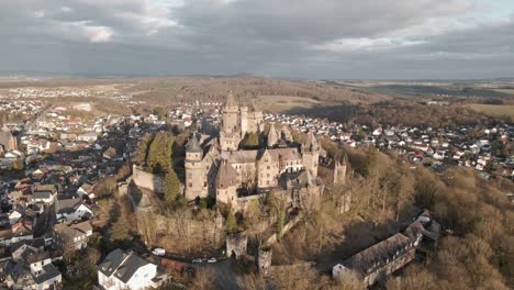 Aerial-footage-of-an-ancient-German-castle-on-the-top-of-a-hill-at-sunset