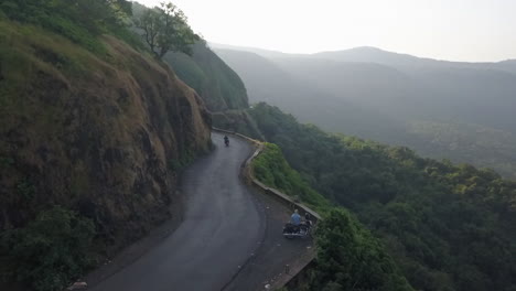 Motorcycle-rides-down-scenic-mountain-side-road-on-hazy-day-in-India