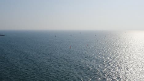 Multiple-windsurfers-with-red-sails-surf-the-clear-Mediterranean-sea-reflecting-sunlight-from-the-bright-sun-near-Herzeliya-in-Israel
