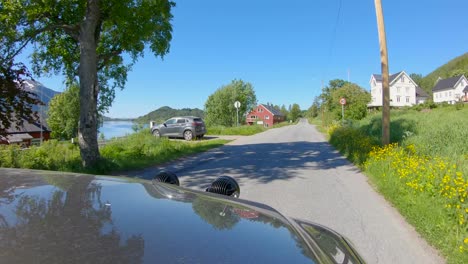 Driving-in-Northern-Norway,-Hood-view-through-Norwegian-Village-with-narrow-Roads,-Slow-motion