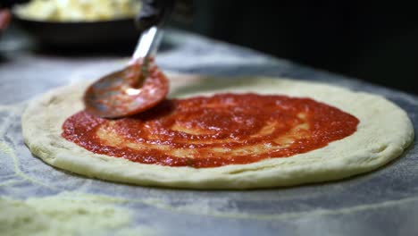 Metalllöffel,-Der-Eine-Tomatensauce-Auf-Einen-Pizzateig-Aufträgt,-Um-Eine-Pizza-Zu-Machen