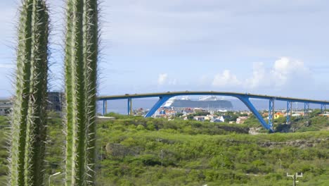 Queen-Juliana-Bridge-in-the-city-of-Willemstad-with-a-cruise-ship-docked-behind-in-Curacao,-Caribbean