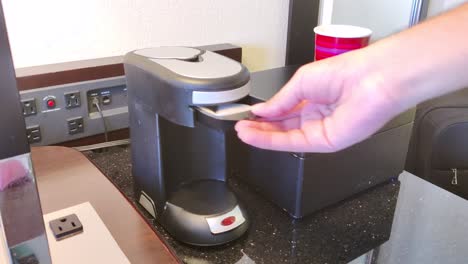 Ein-Mann-Fängt-An,-Kaffee-Zuzubereiten,-Schiebt-Eine-Kaffeepackung-In-Die-Maschine-Und-Stellt-Eine-Tasse-In-Die-Kaffeemaschine.-Videohintergrund-In-4K-|-Mann-Bereitet-Morgens-Kaffee-Zum-Frühstück-Zu