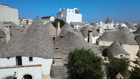 Aerial-drone-close-shot-of-trullis,-small-houses,-whitewashed-stone-huts-with-conical-roof