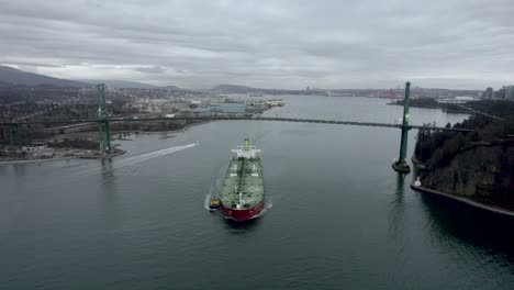 Barge-and-pilot-boat-sailing-on-Burrard-Inlet-fjord-under-Lions-Gate-Bridge,-Vancouver-in-Canada