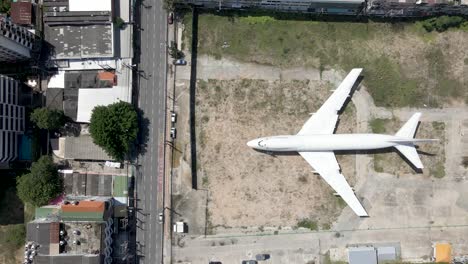 White-Plane-Emergency-landing-in-the-middle-of-a-city,-aerial-fly-over-abandoned-plane