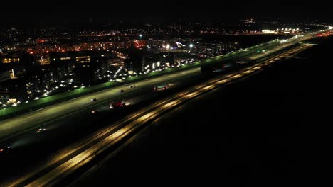 Drone-shot-of-night-traffic-on-a-motorway-showing-cars-and-lanes-of-light-with-Tunnel-and-viaducts-outside-the-city-of-Warsaw,-Poland