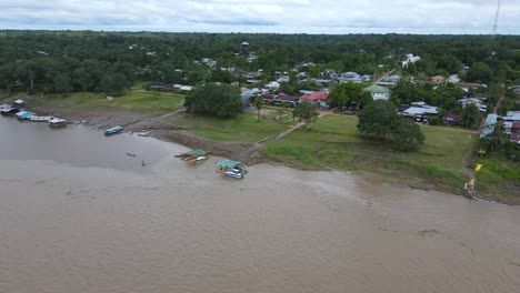 Aerial-view-moving-away-shot,-Scenic-view-of-the-amazon-river-with-small-boats-anchoring-on-a-cloudy-day