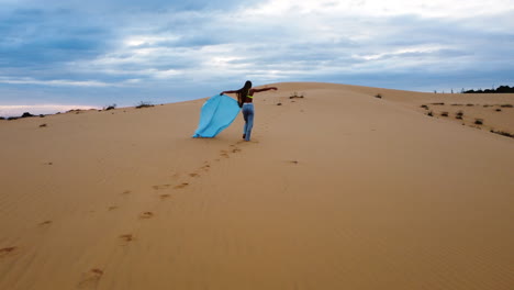 Female-Walking-Along-the-Red-Sand-Dunes-with-Blue-Material
