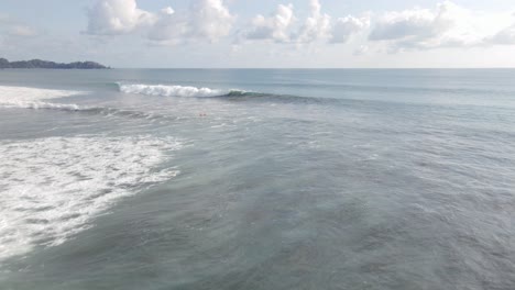 Vista-Aérea-De-Personas-Nadando-En-La-Playa-Dominical-En-Una-Tabla-De-Surf,-Siguiendo-Una-Toma-Amplia