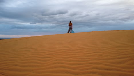 Back-View-Of-A-Woman-Standing-On-Sand-And-Enjoying-The-Sunset-View-In-Red-Sand-Dunes,-Mui-Ne,-Vietnam