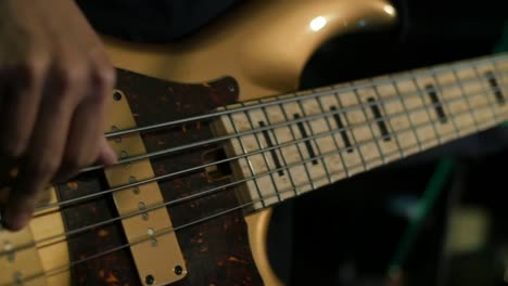 Bass-guitar-being-played-with-colored-stage-lights-lighting-background-in-close-up-and-slow-motion