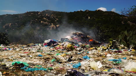 Landfill-pile-of-plastic-trash-garbage-waste-burning-in-rubbish-dump,-toxic-smoke-air-pollution-releasing-unhealthy-particle-in-the-atmosphere
