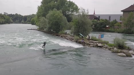Surfer-in-wetsuit-rides-standing-wave-in-Bremgarten,-Switzerland