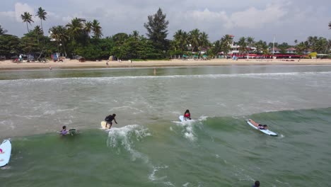 Toma-De-Seguimiento-De-Personas-Surfeando-En-Olas-Suaves-Y-Cayendo-Al-Agua-En-Una-Asombrosa-Playa-De-Arena,-Sri-Lanka