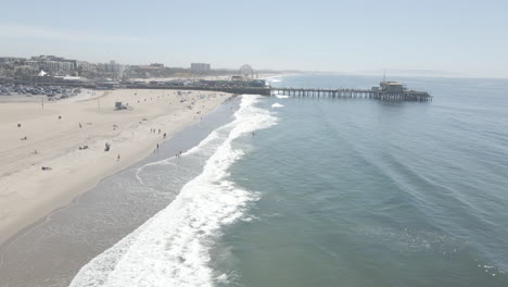 Blick-Aus-Der-Vogelperspektive-Auf-Den-Strand-Und-Den-Pier-Von-Santa-Monica,-Da-Viele-Draußen-Das-Schöne-Wetter-Genießen