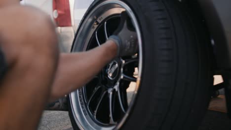 Mechanic-lifts-a-wheel-with-a-new-tire-on-a-race-car-in-slow-motion