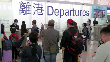 Passengers-wait-in-line-to-go-through-the-security-check-at-Chek-Lap-Kok-International-Airport-departure-hall-in-Hong-Kong,-China
