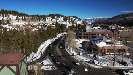 Aerial-view-with-orbit-ascending-of-road-passing-though-snowy-mountain-with-cars-and-people-walking