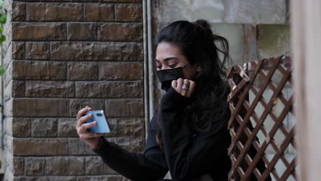 A-young-Muslim-girl-wearing-black-dress-in-mask-clicking-selfie-and-smiling