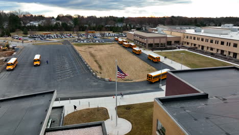School-bus-arrive-at-public-high-school-building-in-USA