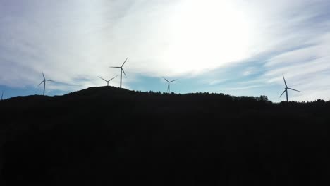 Silhouette-Von-Windkraftanlagen-Vor-Hellem-Himmel-Mit-Dunklem-Bergvordergrund---5-Rotierende-Turbinen-Im-Windpark-Midtfjellet-Fitjar-Norwegen